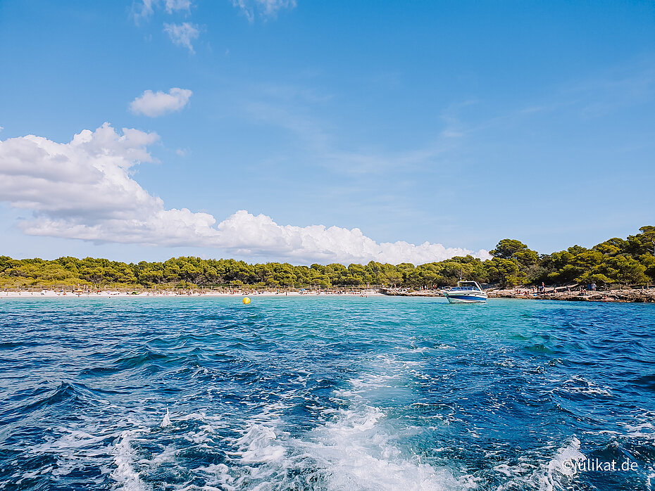 Weiße Gischt schäumt über dem türkisen und azurblauen Meer vor der Bucht auf.