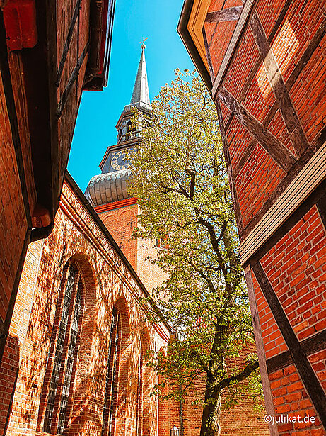 Durch die Gassen zwischen Fachwerk und Ziegelsteinen mit Blick zur Kirche