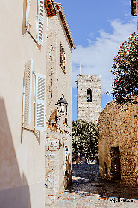 Der Blick durch die Gasse führt zu einem steinernen Turm.