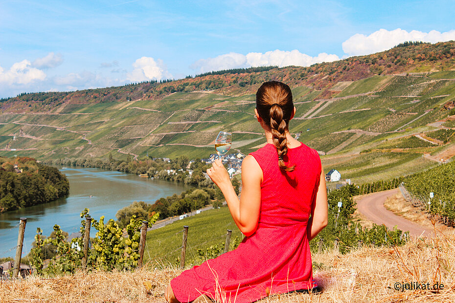 Autorin mit Weinglas auf dem Weinberg sitzend