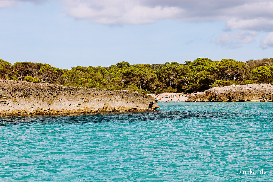 Traumhafte, türkisene Bucht mit Sandstrand und flachen Felsen