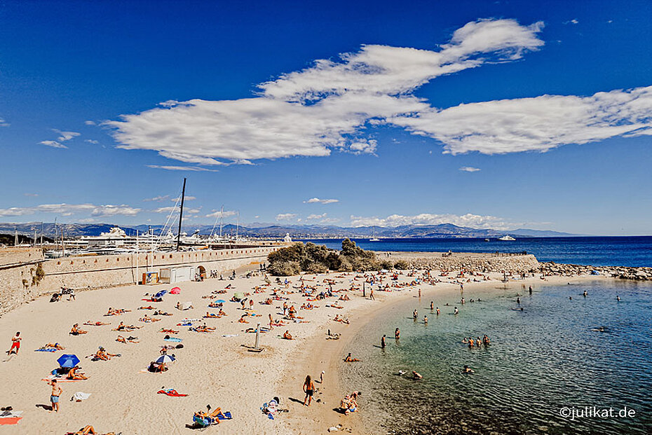 Ausblick über den sonnigen und gut besuchten Sandstrand vor der Stadtmauer