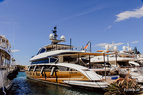 Eine riesige weiß-goldene Yacht liegt im Hafen.