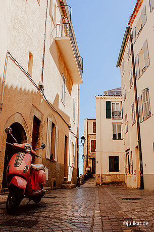 Ein pinker Motorrollersteht in der verschlafenen Gasse.