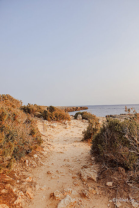 Ein steiniger Sandweg führt entlang der balearischen Küste.