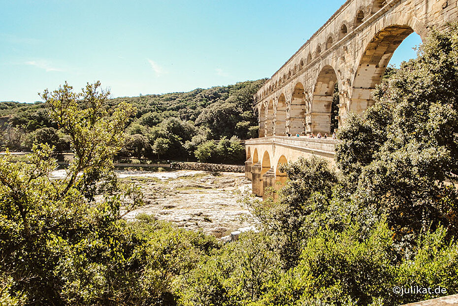 Blick durch üppiges Grün zur Pont du Gard