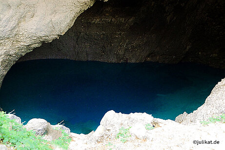 Dunkle Höhle in der Felswand mit Wasser