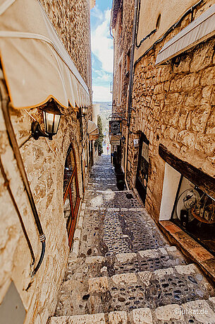 Eine Treppe führt hinab durch eine mediterrane Gasse.